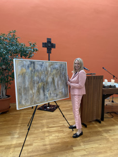 Die Künstlerin Irene Lösel steht vor einem abstraktem Kunstwerk